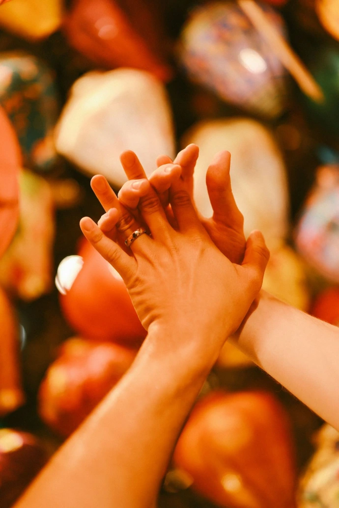 Two hands clasped together with colorful background.